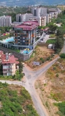 Yeşillikler arasında pek çok evi olan resim gibi bir yaz şehri. Şarjör. Parlayan güneşin altında binalar ve bitkiler