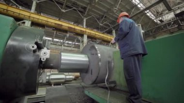 Çalışkan bir işçi, endüstriyel işlemler ve temel imalatın kilit yönlerini gösteren makineleri izliyor. Menkul Kıymetler