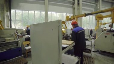 Parlak ve hareketli bir endüstri atölyesi ortamında kendini işine adamış bir işçi ustalıkla makineler çalıştırıyor.