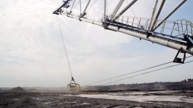 Devasa bir kazıcı, açık bir gökyüzünün altındaki geniş bir maden sahasında çeşitli materyalleri verimli bir şekilde çıkarıyor. Menkul Kıymetler