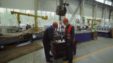 Güvenlik teçhizatı kullanan iki işçi modern endüstriyel tesis çevresindeki çeşitli materyalleri inceliyor. Menkul Kıymetler