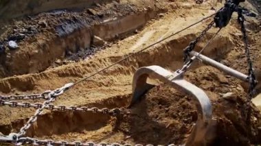 Zincirlere sıkı sıkıya bağlı bir kazı kovasının yakından görüntüsü. Toprak kazısı için tamamen hazır.