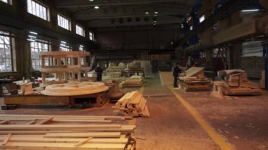 Geniş bir marangoz fabrikası. Çeşitli makinelerle, kereste ve kereste yığınlarıyla dolu. Menkul Kıymetler