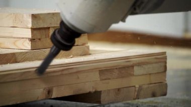 Burada, atölye alanında istiflenmiş tahtalar üzerinde çalışan çivi tabancasının detaylı bir görüntüsü var. Menkul Kıymetler