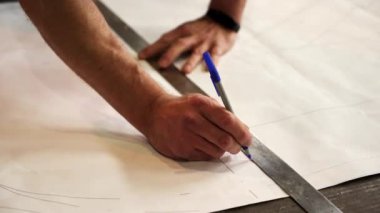 Tasarımda kesin ölçümleri sağlamak için bir cetvel ve kağıt üzerine bir işaret kullanan ellerin yakından görüntüsü. Menkul Kıymetler