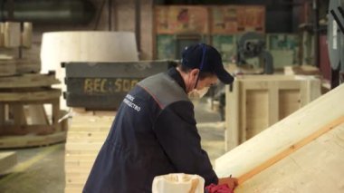 Kendini işine adamış bir işçi bir atölyede titizlikle odun parçalarını ölçüyor, hassasiyet ve ustalık üzerine yoğunlaşıyor. Menkul Kıymetler