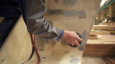 Atölye ortamında, yetenekli bir zanaatkar ahşap bir yüzeyi etkin bir şekilde pürüzsüz kılmak için zımpara makinesi kullanır. Menkul Kıymetler