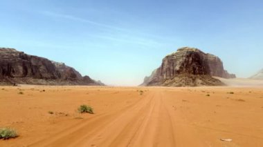 Geniş bir çöl manzarasının nefes kesici görüntüsü sonsuz kumlarla çevrili görkemli kayalık oluşumları sergiliyor. Eylem