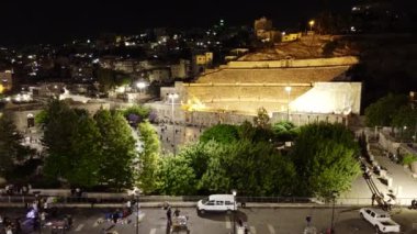 Çarpıcı bir gece manzarası aydınlatılmış mimarisi ve canlı yeşilliğiyle tarihi bir mekanı gösteriyor. Eylem
