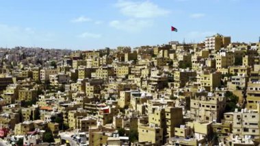 Amman 'ın canlı şehir manzarası açık mavi gökyüzünün altında yoğun binaların çarpıcı bir görüntüsünü sunuyor. Eylem