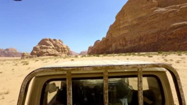Engebeli bir araç Wadi Rum çölünde nefes kesici kaya oluşumları sergiliyor. Eylem