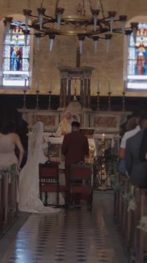 Kilisedeki düğün töreninin arka görüntüsü. Başla. Kilisedeki nişan töreninde bir sürü insan var. Kilisede rahiple düğün töreni..