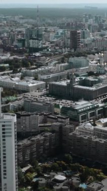 Yükseltilmiş yaz şehrinin helikopter görüntüsü. Stok görüntüleri. Gökdelenleri ve evleri olan şehir merkezinin güneşli manzarası ve turistlerin yürüdüğü küçük bir gölet. Yüksek kalite 4k görüntü