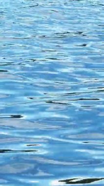 Mavi sudaki güzel dalgaların yakın çekimi. Kavram. Deniz suyunun yüzeyinde mavi dalgalar. Su dalgalanmalarının yüzeyinde mavi gökyüzünün yansıması.