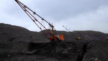 Gri bulutlarla dolu bulutlu bir gökyüzünün altında ağır makinelerin çalıştığı detaylı bir sahne. Menkul Kıymetler