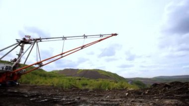 Bulutlu bir gökyüzünün altında yuvarlanan tepelere karşı çeşitli makineler kuran hareketli bir inşaat alanı. Menkul Kıymetler