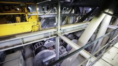 Bu görüntü endüstriyel makinelerin detaylı bir görünümünü, üstteki yapıları ve mekanik bileşenleri vurguluyor. Menkul Kıymetler