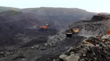 Geniş bir kömür madeni arazisinde çalışan makineleri gösteren geniş çaplı madencilik operasyonlarının geniş bir hava görüntüsü. Menkul Kıymetler