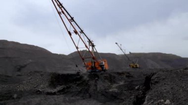 Kazıcılar, engebeli arazinin ortasında güçlü endüstriyel ekipmanlar sergileyen bir maden sahasında aktif olarak çalışıyorlar. Menkul Kıymetler