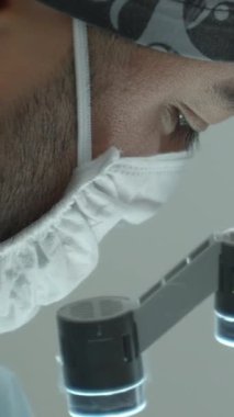 Ameliyathanede profesyonel gözlüklü bir cerrah. Başla. Dürbünlü gözlüklü bir doktorun yan görüntüsünü kapat.