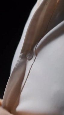 Beyaz gömlekli bir adam karanlık bir odada düğmeleri bağlar. Stok görüntüleri. İş adamı giyiniyor.