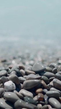 Birçok deniz taşının üzerinde köpüklü deniz suyu yüzeyi. Başla. Yaz denizinin mavi dalgaları ve çakıl taşı kıyıları