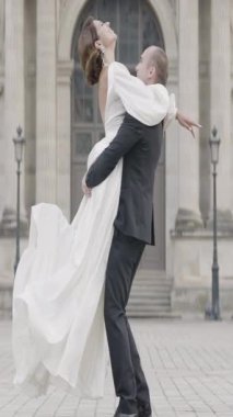 Takım elbiseli ve uzun elbiseli güzel bir çift şehir sokaklarında poz veriyor. Başla. Gelin ve damat düğün fotoğraflarında