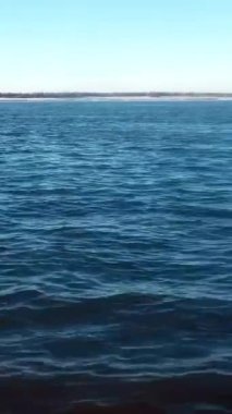Mavi dalgalar üzerinde hareket eden tekneden güzel bir manzara. Şarjör. Ufuktaki sahilin arka planındaki mavi deniz dalgalarının nefes kesici görüntüsü. Mavi dalgalarda hızlı hareket.