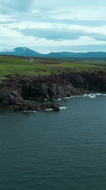 Bulutlu bir günde dağların arkasındaki kayalık kıyı manzarası. Şarjör. Bulutlu bir yaz gününde kayalık kıyıları olan güzel kuzey manzarası. Dağ ufukları ve bulutlu gökyüzü ile kayalık okyanus kıyıları.