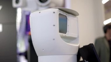 Pürüzsüz ve modern bir robot, inanılmaz bir yeniliğin altını çizerek bir teknoloji sergisinde belirgin bir şekilde sergileniyor. Medya