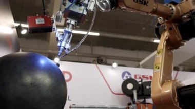 Dubai, BAE - Haziran 2024: Yenilikçi teknoloji sergisinde bir sanat robotik kolu büyük küresel bir nesneyle etkileşim halindedir. Medya