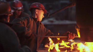 İşçiler, bir fırın fabrikasında eriyik metali ustalıkla işleyerek beceri ve hassasiyetlerini gösteriyorlar. Menkul Kıymetler