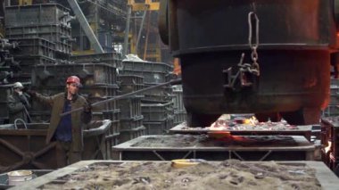 Bir endüstriyel işçi, metal işçiliğini gösteren bir dökümhane ortamında erimiş metali işliyor. Menkul Kıymetler