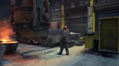 Becerikli bir işçi, etrafındaki erimiş metal ve ağır makinelerle dolu bir dökümhaneyi ustalıkla dolaşır. Menkul Kıymetler