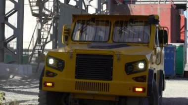 Güçlü ve güçlü bir sarı kamyon, yoğun bir endüstriyel çevrede ustalıkla yol alıyor. Menkul Kıymetler