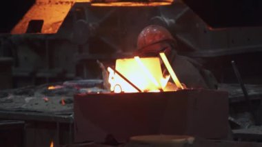 Erimiş metalin hareketli bir sahnesiyle dolu bir dökümhaneye ustalıkla dökülmüş, sanayi işçiliği sergileniyor. Menkul Kıymetler