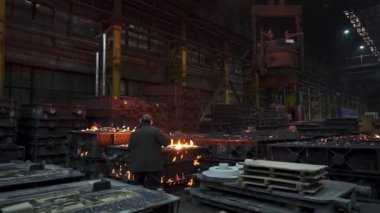 Yetenekli bir işçi, çağdaş bir endüstriyel dökümhane ortamında erimiş metali özenle yönetiyor. Menkul Kıymetler