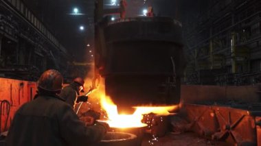 Loş bir endüstriyel dökümhane ortamında, yetenekli işçiler titizlikle erimiş çeliği döküyorlar. Menkul Kıymetler