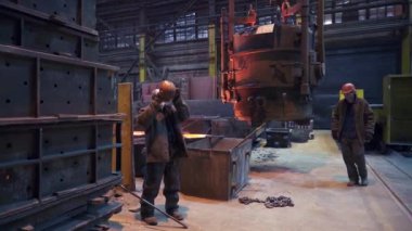 İki yetenekli işçi, endüstriyel fabrika ortamında büyük endüstriyel makineler kullanıyor. Menkul Kıymetler