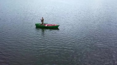 Huzurlu ve sakin bir sahne, onu çevreleyen huzurlu suların tadını çıkaran yalnız bir kanoyu güzel bir şekilde tasvir eder. Menkul Kıymetler