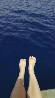 Rahatlama teması için ideal, derin mavi okyanus sularına nazikçe batan ayak parmaklarının huzurlu ve huzurlu bir görüntüsü. Dikey şarjör. Eylem