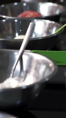 Tabaklarda farklı malzemeler olan masa manzarası. - Sanat. Un, patates, ahşap kesim tahtasının yanında yeşil soğan ve yemek pişirme konseptiyle metal tabaklara yakın durun.