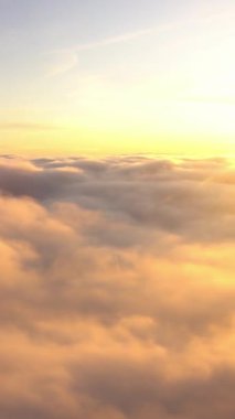 Gökyüzündeki uçaktan, gün doğumundan ve bulutlardan inanılmaz manzara. Cennet, altın güneş ve mavi arka planda yumuşak beyaz bulutlarla aydınlanıyor..