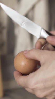 Kadın elinin yumurtayı bıçakla kırması ve patates püresinin içine çiğ beyaz ve yumurta sarısı koyması, pişirme konsepti. Başla. Mutfakta patates püresi ve yumurta..