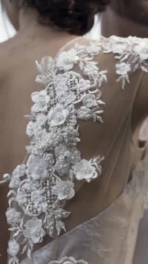 Güzel, beyaz bir gelinliğin arkası... narin çiçekli ve arkası kesilmiş genç bir gelinin. Parlak arka planda gelin ve damadı kucaklayan aşıklar.