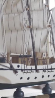 Ahşap gemi oyuncak modeli, aydınlık odada ahşap bir masanın üzerinde duruyor, hobi konsepti. Yelkenli geminin küçük figürünü kapat..