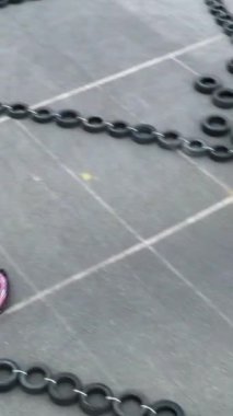 Kırmızı küçük araba kullanan, koruyucu üniformalı ve pistin kenarında siyah lastikten yapılmış bir kask takan birinin hava görüntüsü. Go kart yarışçısı pistte, motor sporu konseptinde boğuşuyor.