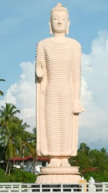 Tsunami Honganji Vihara, Hikkaduwa, Sri Lanka. Başla. Yeşil palmiye ağaçları ve mavi bulutlu gökyüzü arasında güzel beyaz heykel