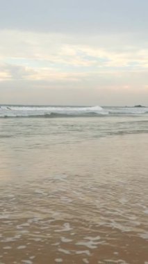 Uzun dalgaları ve mavi bulutlu gökyüzü olan güzel kumlu bir sahil manzarası. Başla. Tropikal adasında güzel sakin bir sahil