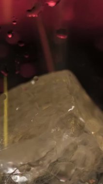Koyu arka planda kırmızı loş ışık ile buzlu bardağa taze alkollü içecek dökmek. Stok görüntüleri. Kokteyl hazırlama sürecini kapat ve bardağa içecek ekle..